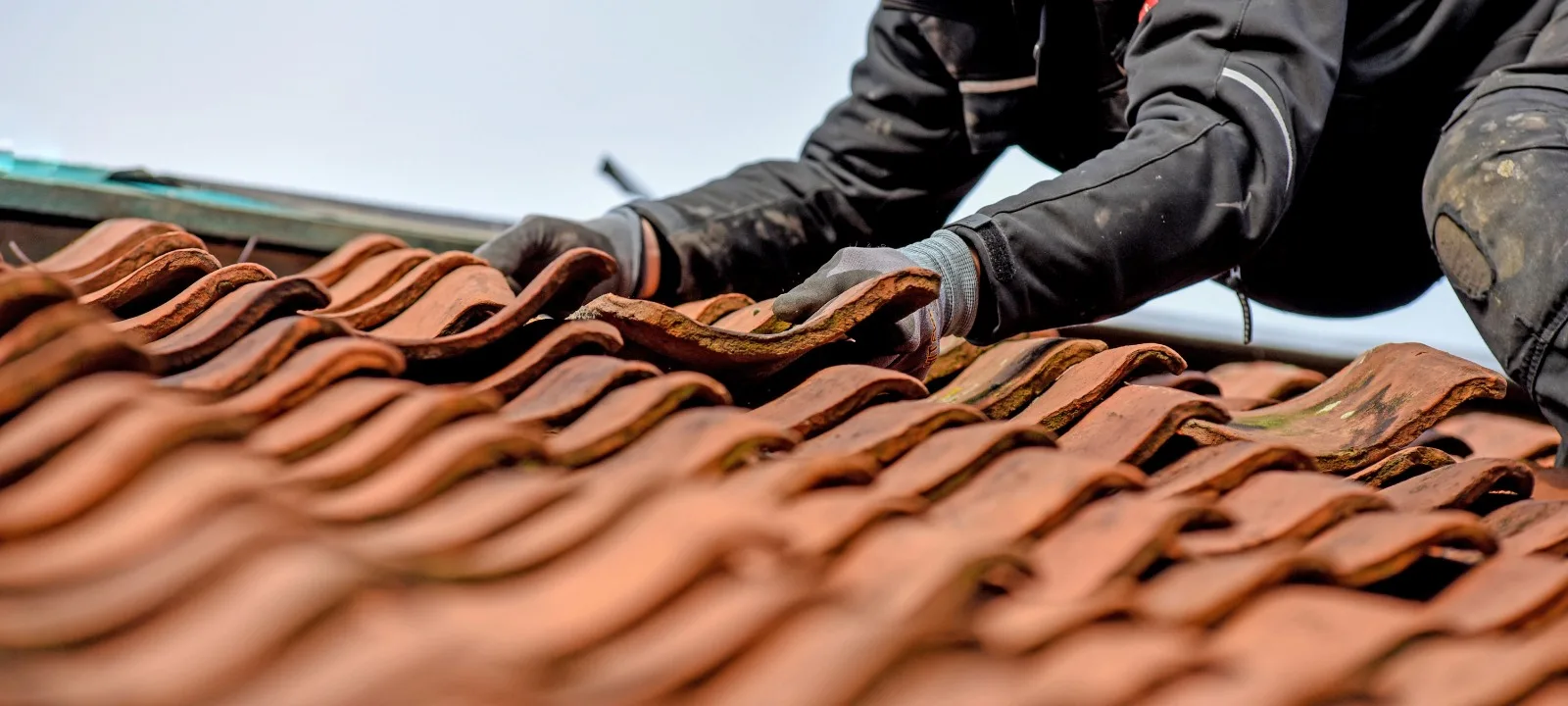 Dachdecker bei der Anpassung von Terrakotta-Dachziegeln auf einem Steildach